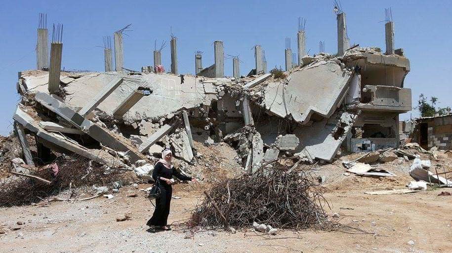 Enas in front of a destroyed building