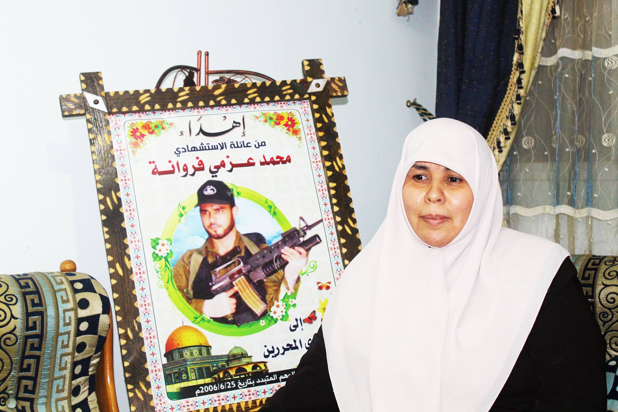 Um Mohammed with a photo of her son in military uniform
