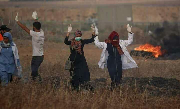 Paramedics raise their hands to show Israeli troops they have no weapons