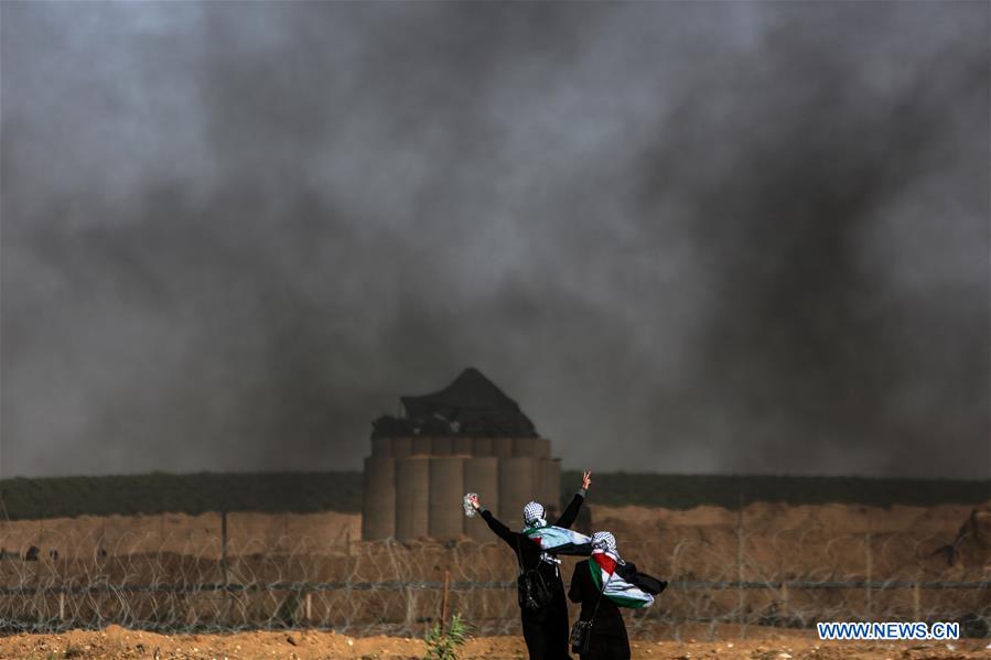Woman in Gaza standing at border looking into Israel over the fence