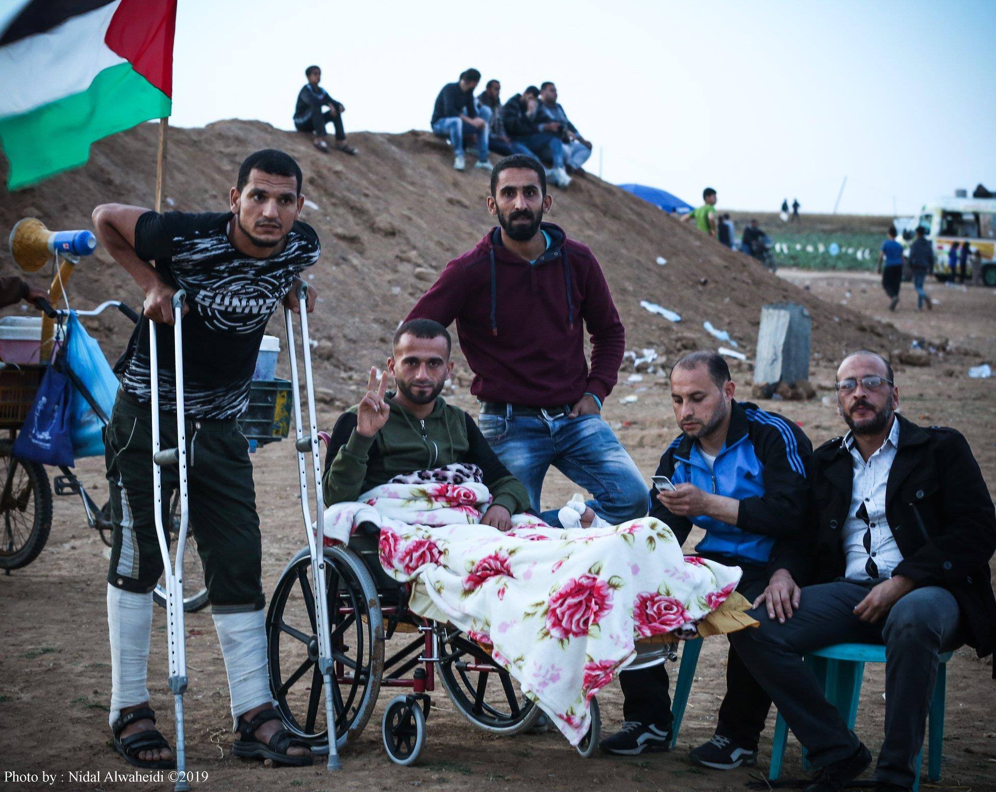 Young man in wheel chair surrounded by friends at the Gaza border