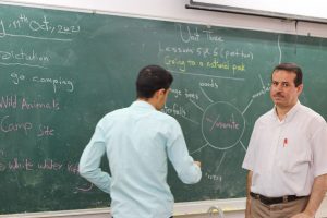 young man with teacher at chalkboard