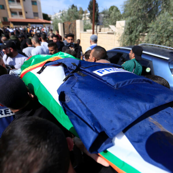 body draped with Palestinian flag and press jacket