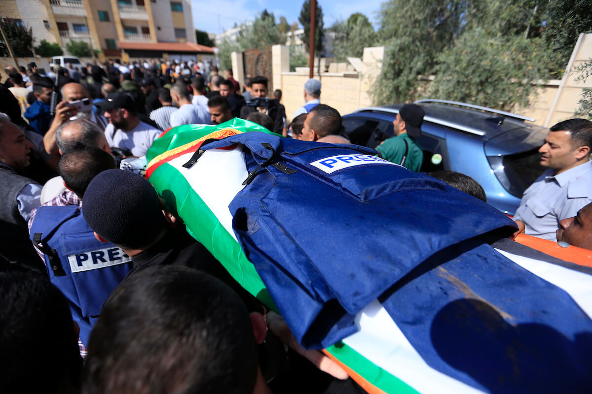 body draped with Palestinian flag and press jacket