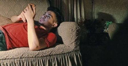 young man lying on couch looking at phone