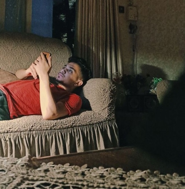 young man lying on couch looking at phone