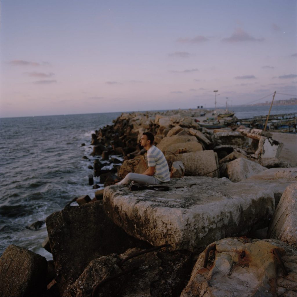 Man sitting on rocks by the sea.