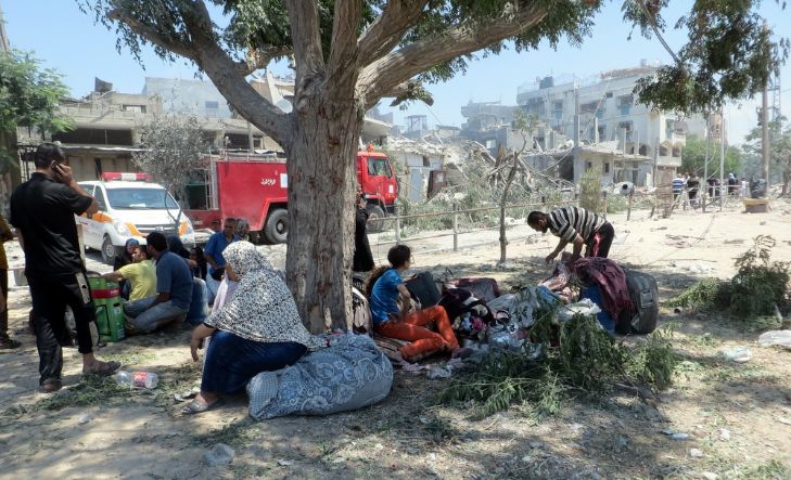 Refugees sitting under tree.