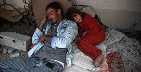 Man and child sleeping in rough shelter.
