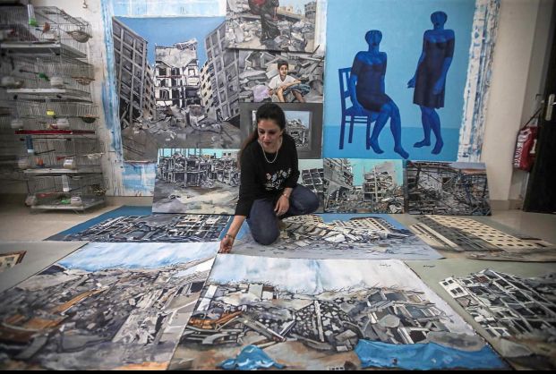 Palestinian artist Maha Al-Dayya alongside her paintings.