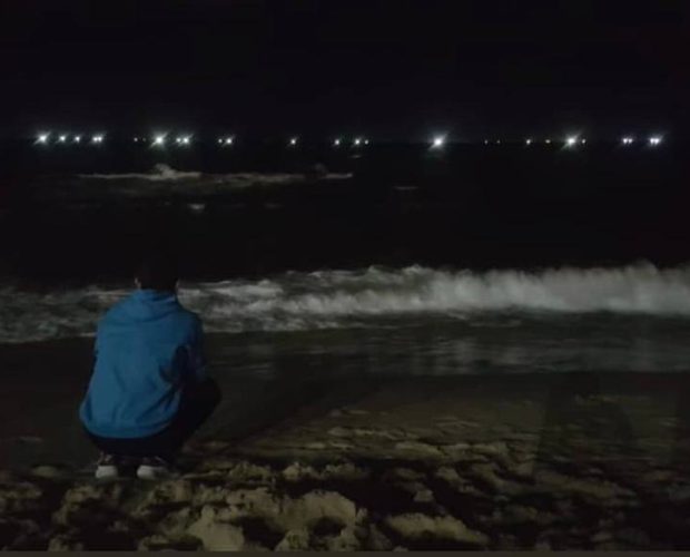 Young man on beach at night.