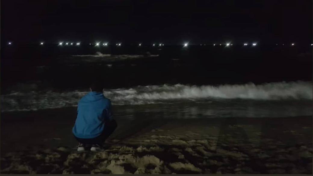 Young man on beach at night.