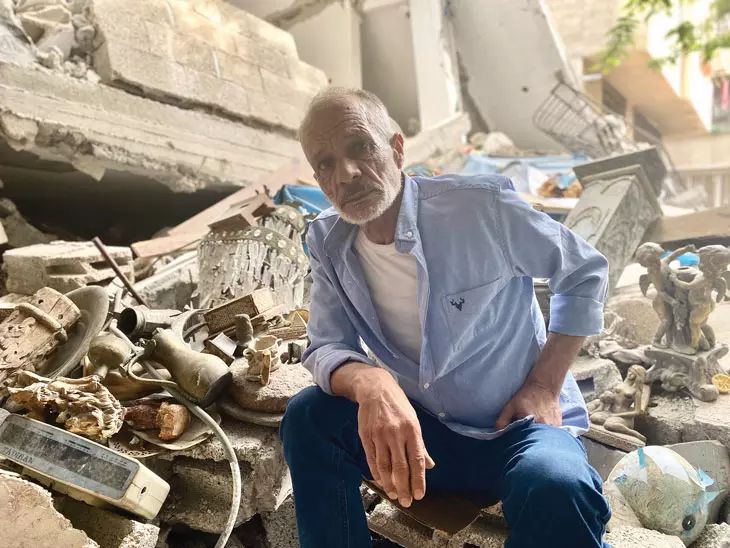 Man sitting amidst rubble.