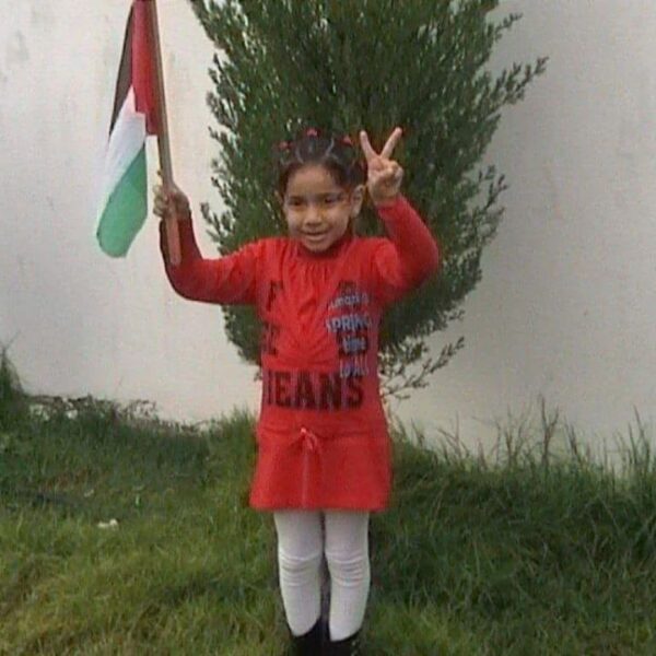Young girl waving Palestinian flag.