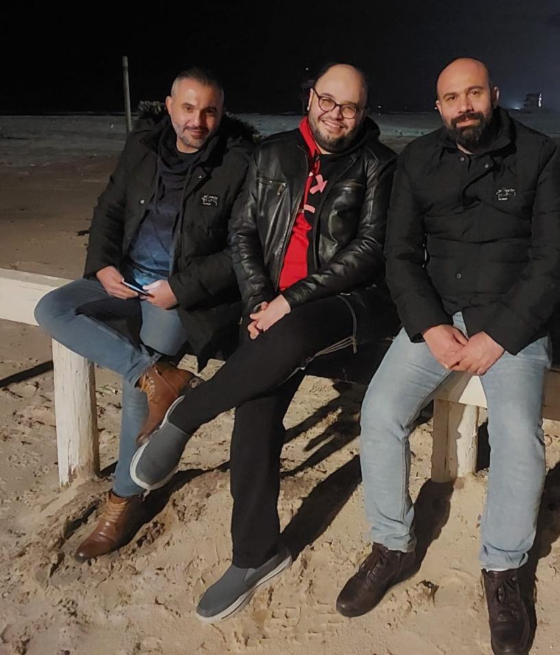 Three young men sitting on Gaza beach.