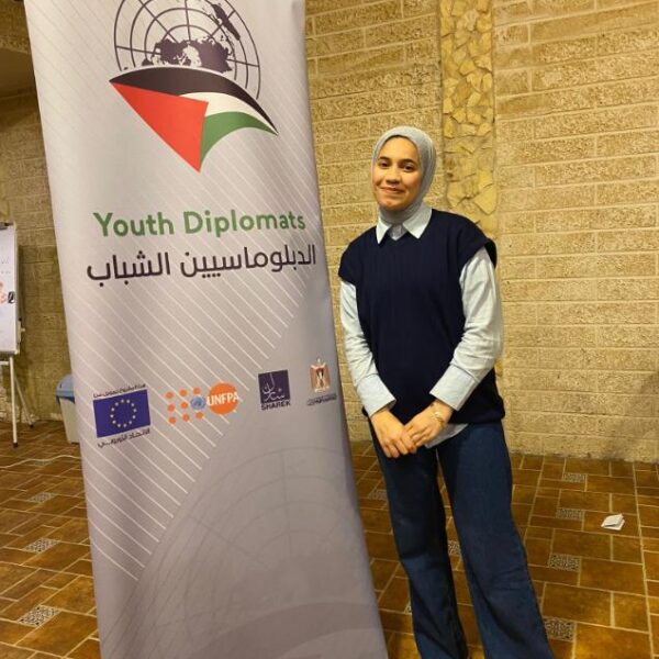 young woman next to banner with words "Youth Diplomats."
