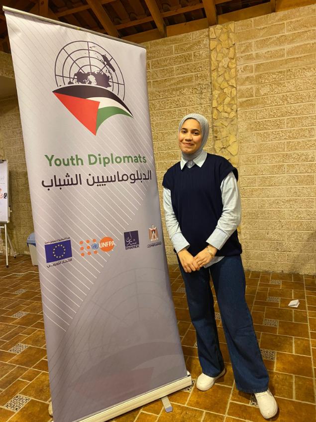 young woman next to banner with words "Youth Diplomats."