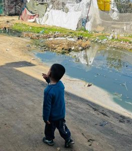 Young boy walking past stagnant water in the road