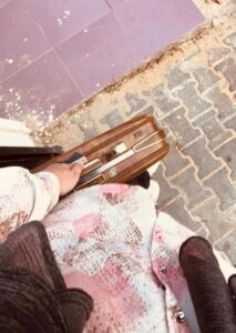 Bird's eye view of a suitcase on the ground next to a young woman.