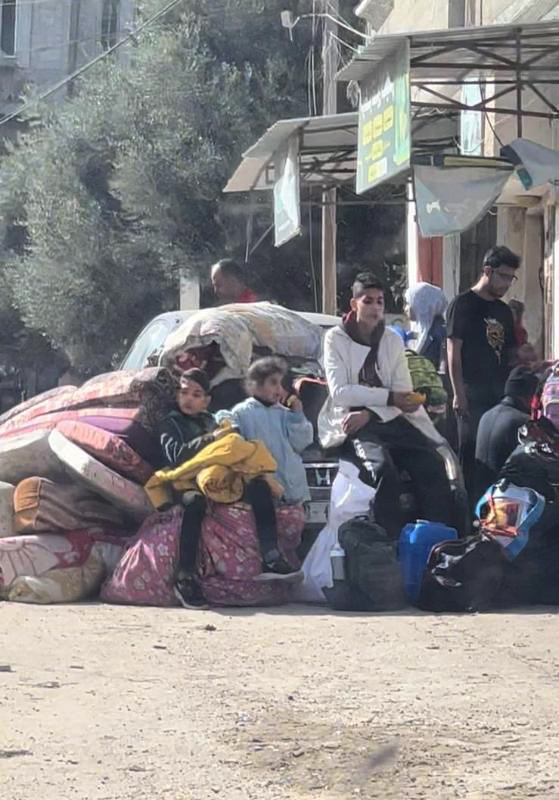 Children on side of road with a pile of possessions.