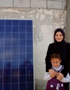 A woman and her daughter by a solar panel.