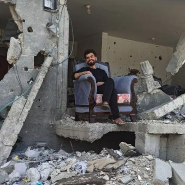 Momen Alsammak, sitting on upholstered chair among the rubble of his home.