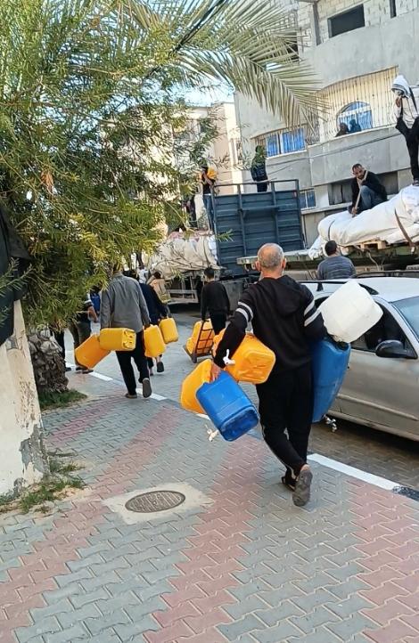 Men carrying water jugs down a street.