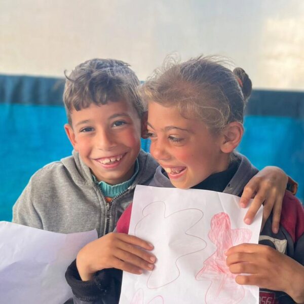 Two children clutching illustrations they drew.