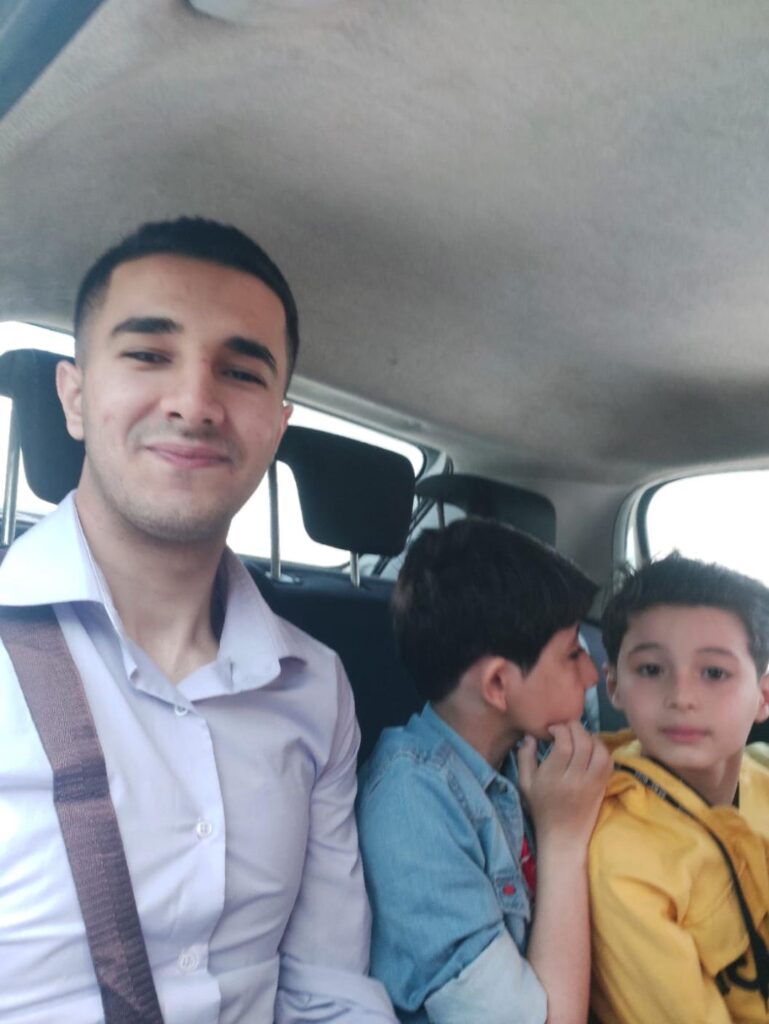 A young man and two boys in nice clothes, in a car.