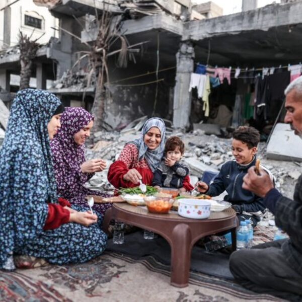 Familyl eating Iftar meal in front of destroyed building in Gaza.