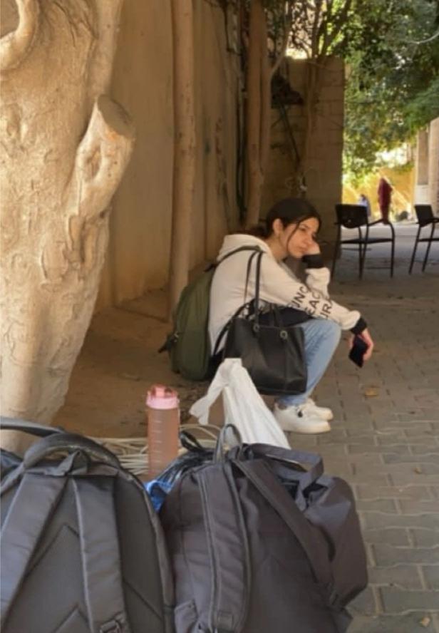 A young woman sitting near backpacks.