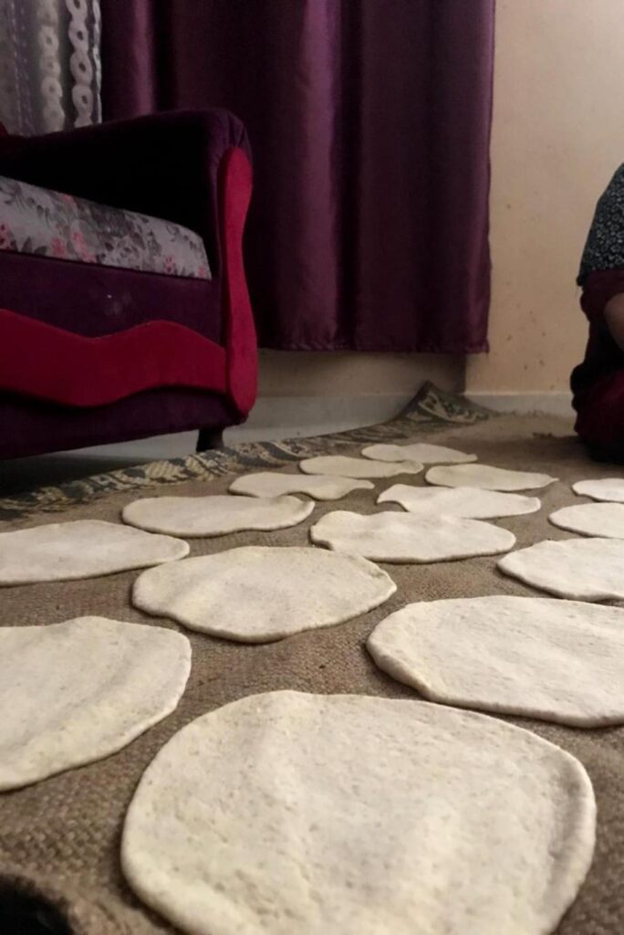 Uncooked bread circles laid out on a rug.