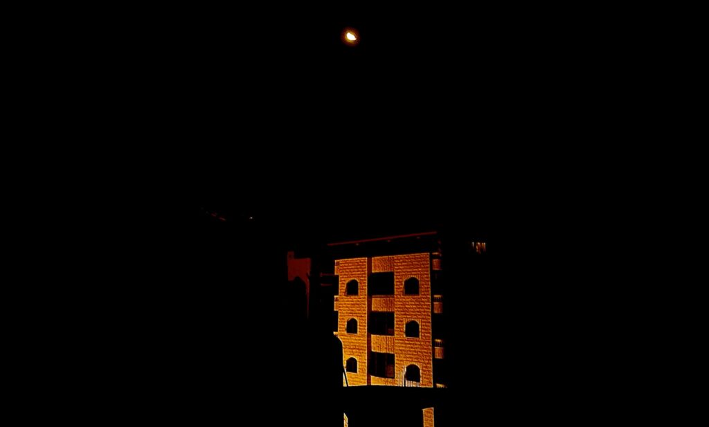 The moon over an apartment building at night in Gaza.