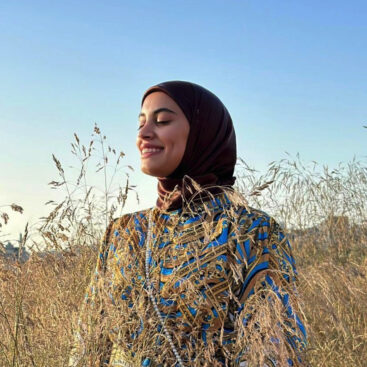 Young woman with hijab and colored dress in a wheatfield.