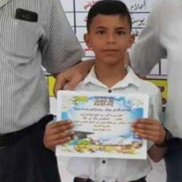 Boy between two adults, holding a school certificate.
