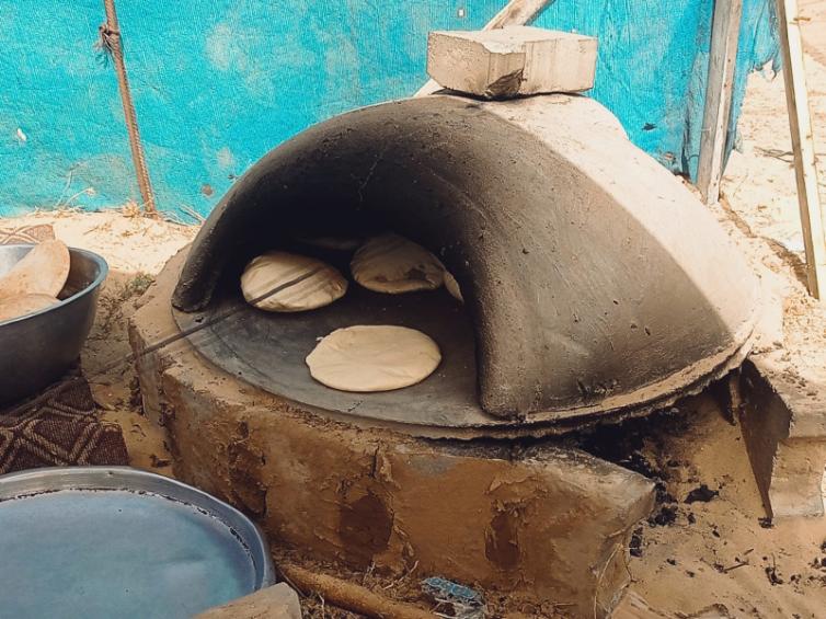 Clay oven with round bread baking.