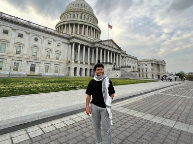 Young man wearing kaffiyeh in front of the U.S. capitol.