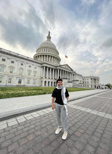 Young man wearing kaffiyeh in front of the U.S. capitol.