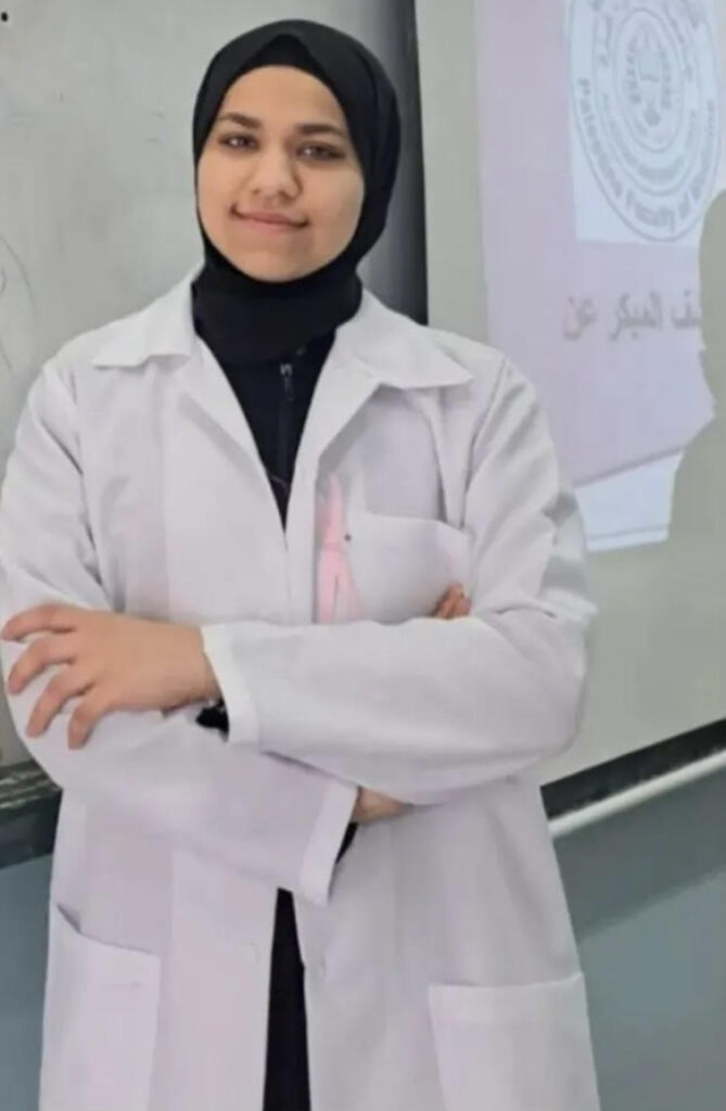 Young woman in white medical coat and hijab.