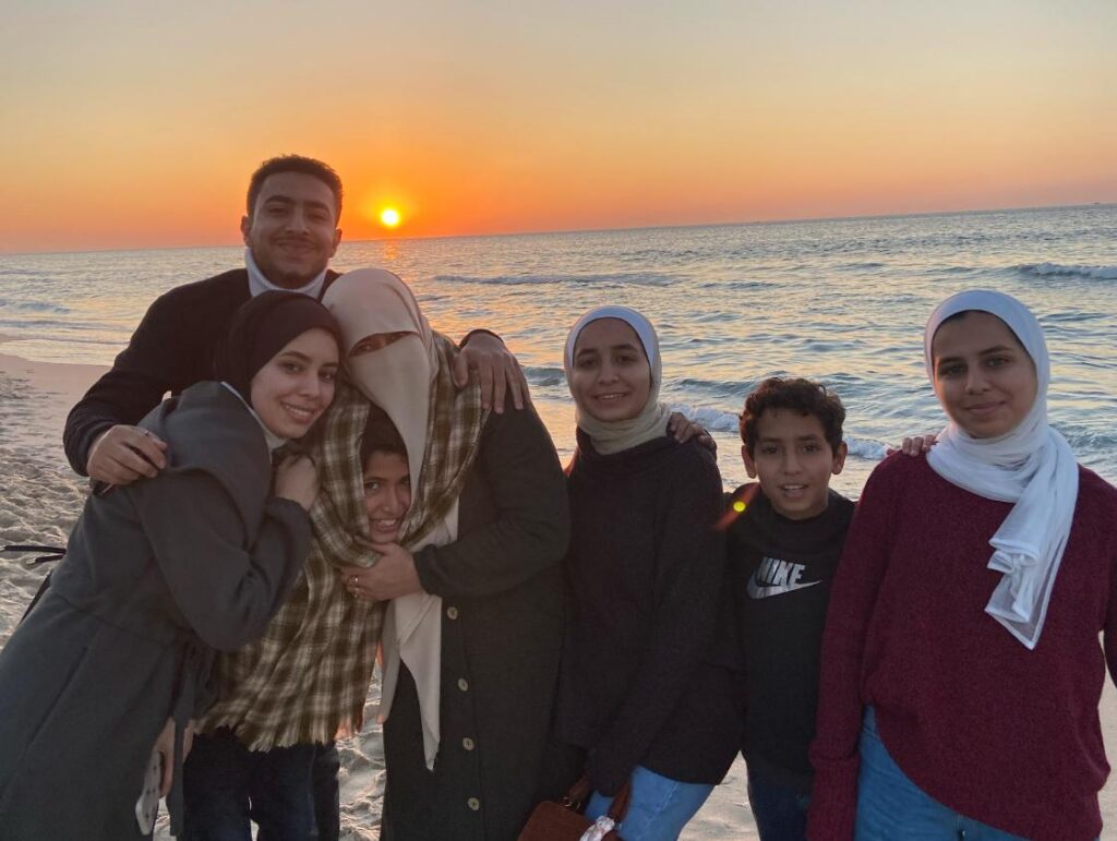 Seven members of the family standing together on the Gaza beach at sunset.