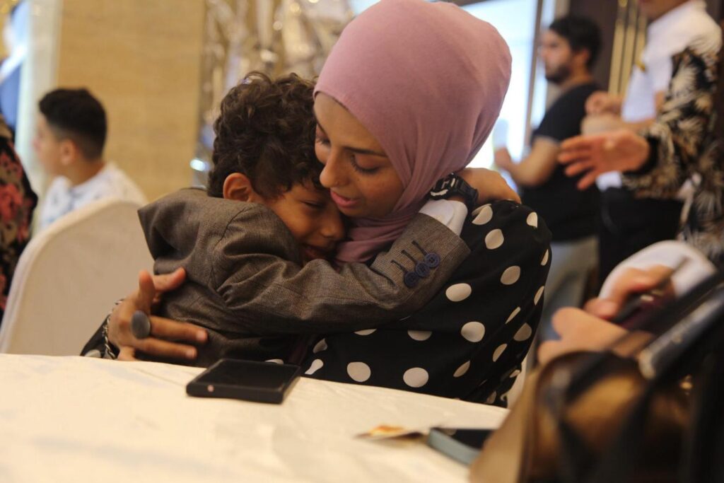 Little boy hugging his mother at a public event.