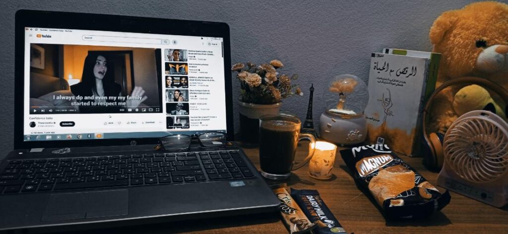 Desk with laptop, candle, candy bar, and other objects.
